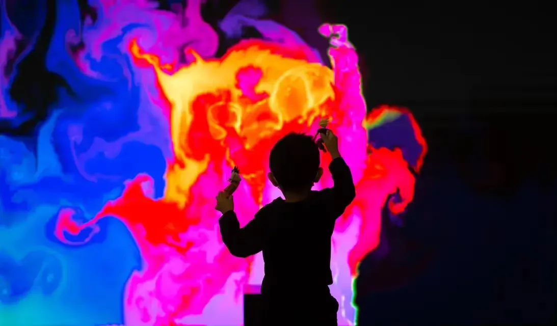 Un enfant devant une œuvre numérique interactive aux couleurs vives